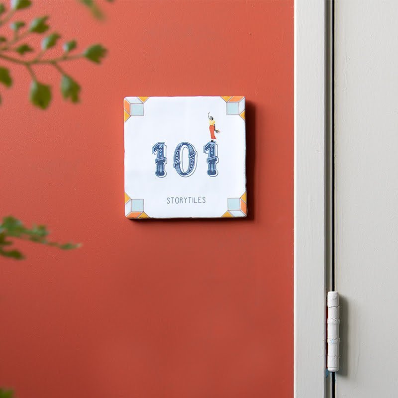 Huisnummer tegeltje met speelse decoratie op rode muur