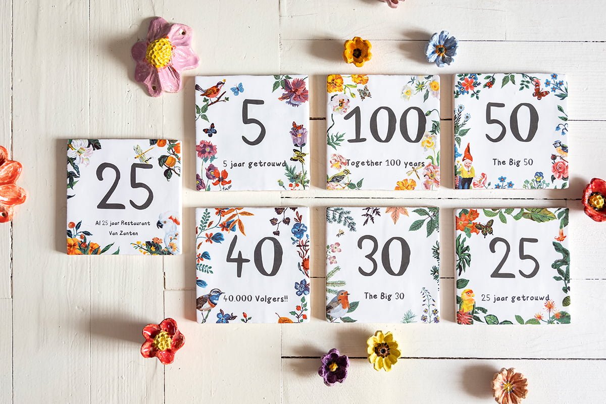 Gepersonaliseerde tegeltjes met kleurrijke bloemen op witte houten ondergrond