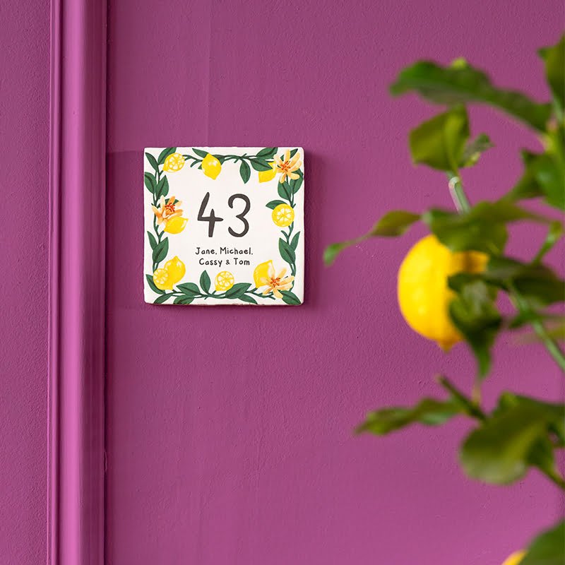 Huisnummer tegeltje met citroenen en bloemen op paarse muur