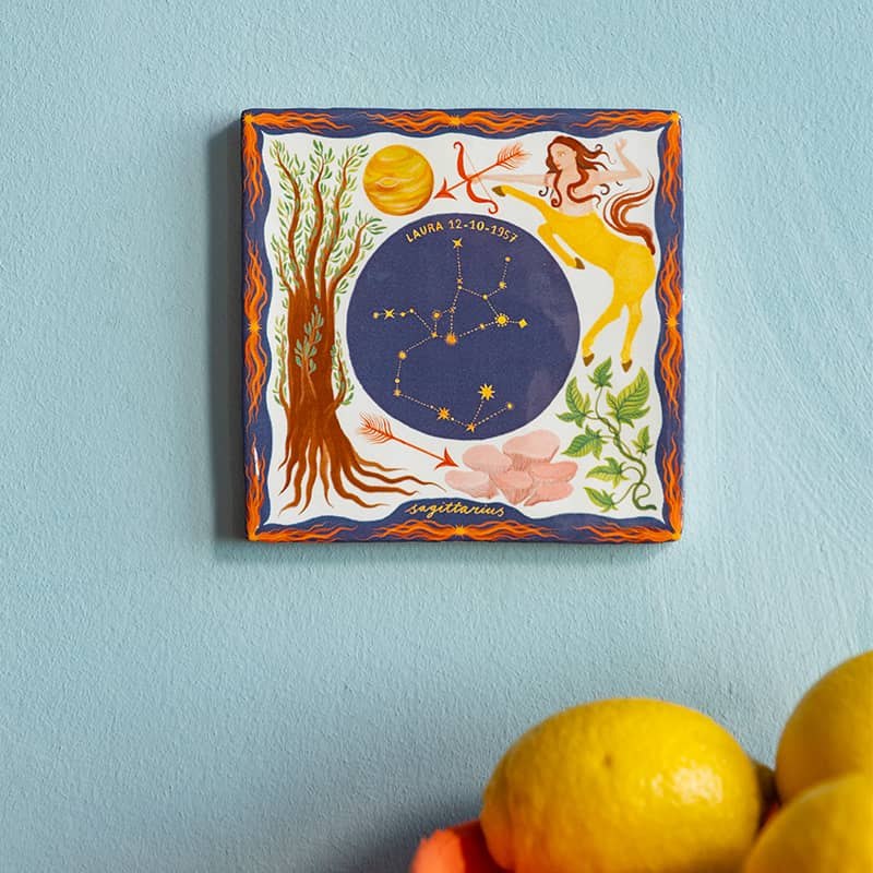 Geboortetegel Boogschutter met kosmische illustraties aan blauwe muur