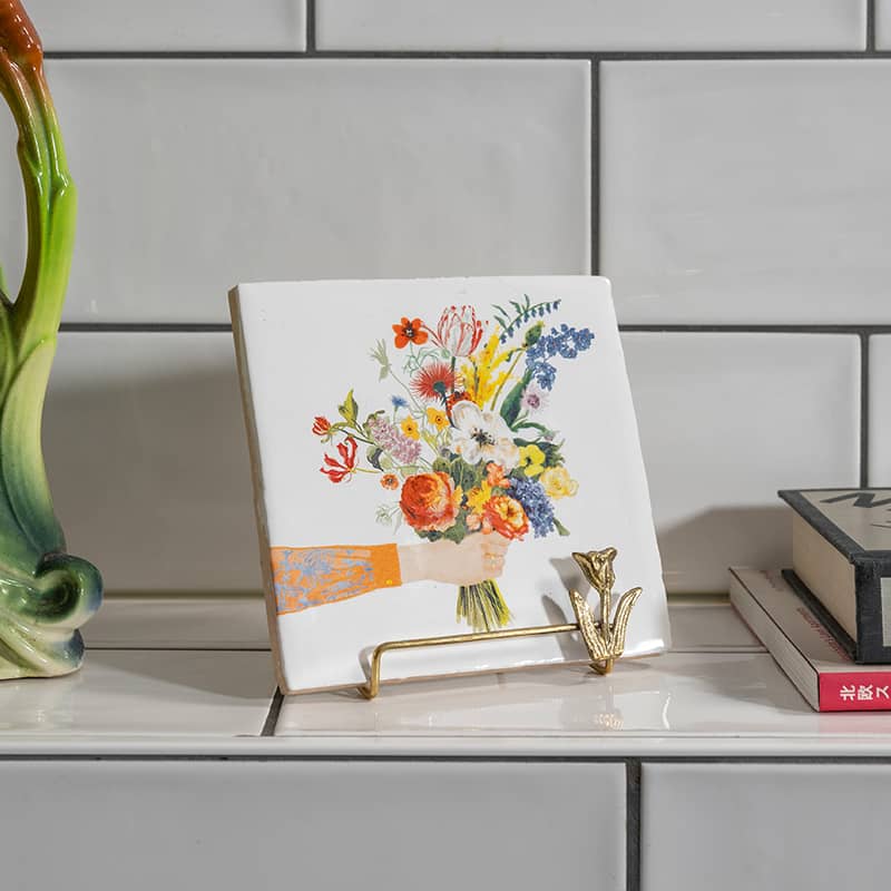 Gouden tegelhouder in bloemenmotief op een wandplankje