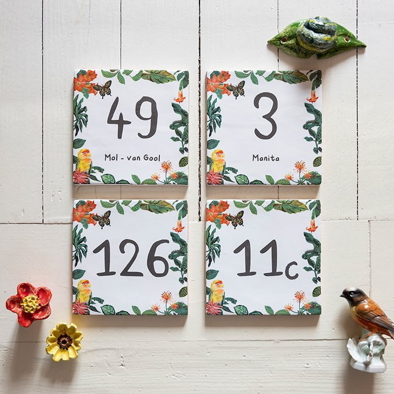 Tegeltjes met huisnummers en bloemenmotief op houten achtergrond
