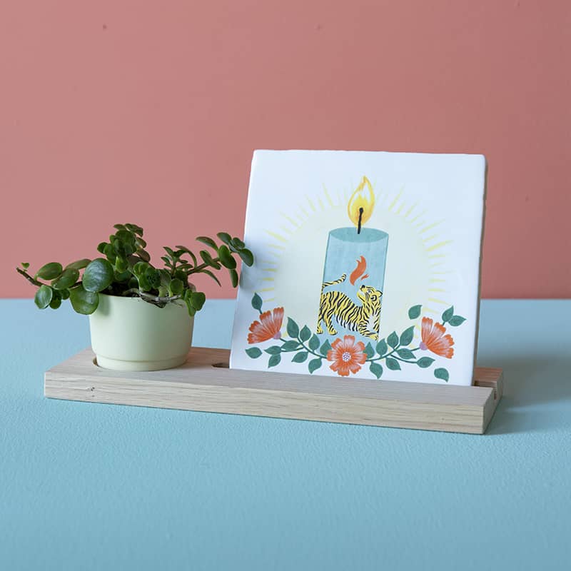 Tegelhouder met tegeltje en plantje op blauwe tafel