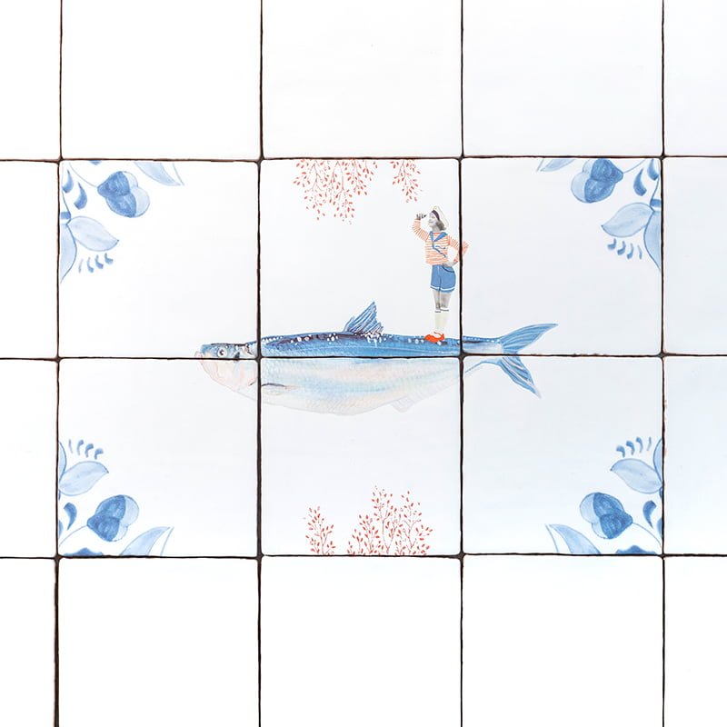 Tegeltje met vis en figuur, omlijst door blauwe bloemen