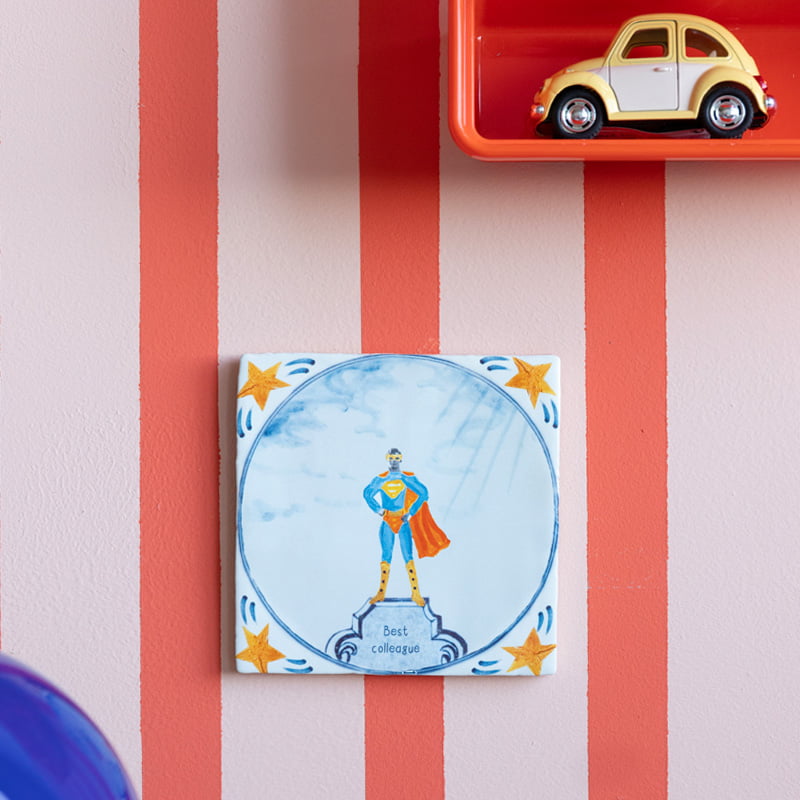 Gepersonaliseerd tegeltje met superheld en sterren, aan gestreepte muur
