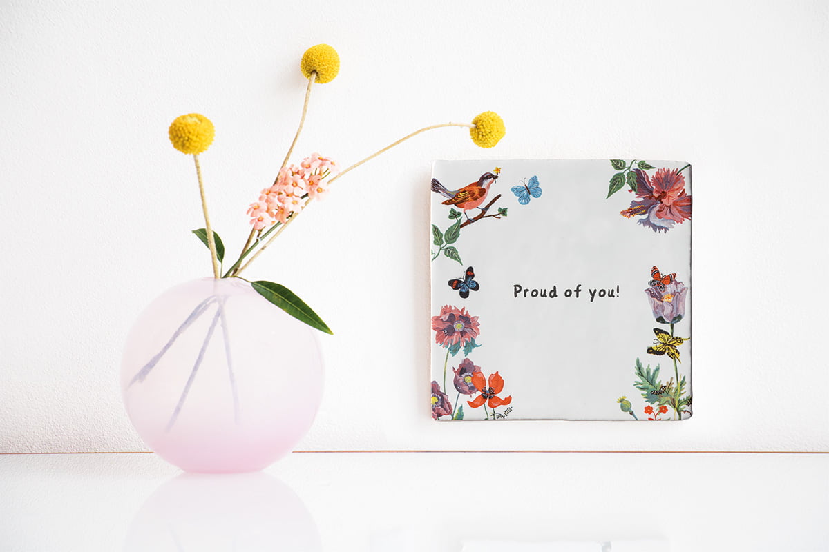 Tegeltje met bloemen en vogels aan de muur