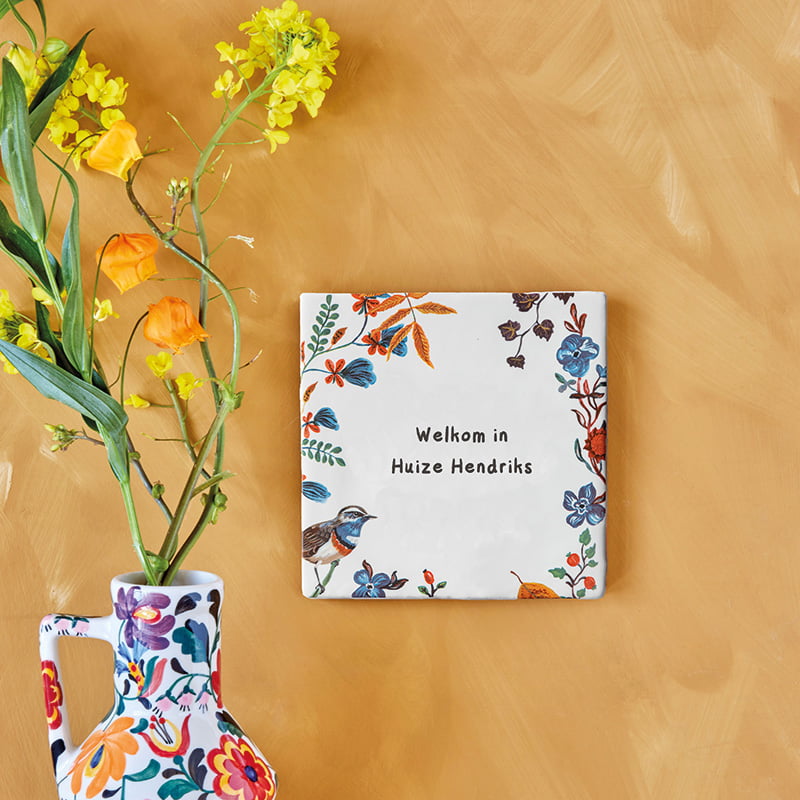 Tegeltje met bloemen en tekst op houten oppervlak