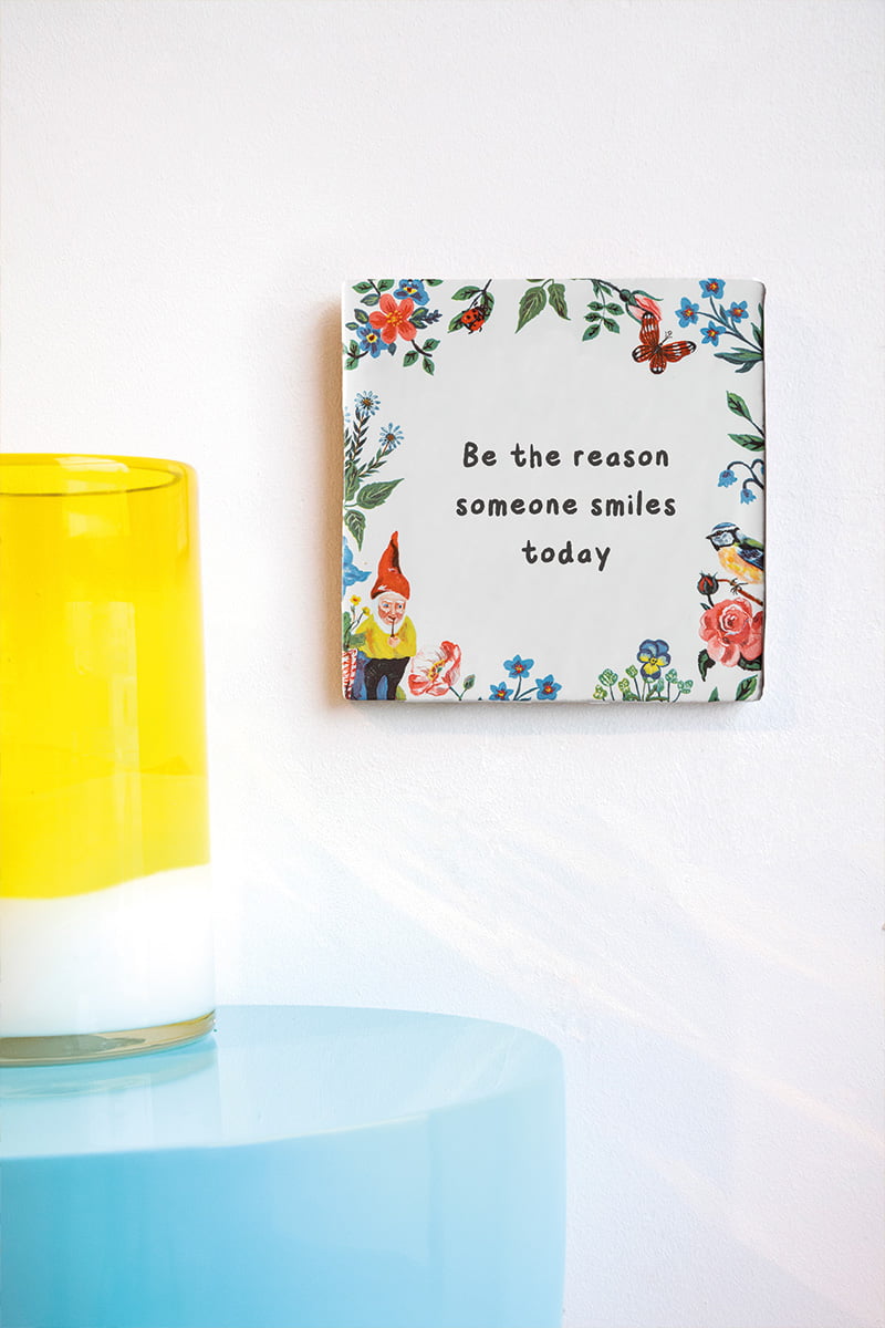 Tegeltje met tekst en kleurrijke bloemen aan de muur