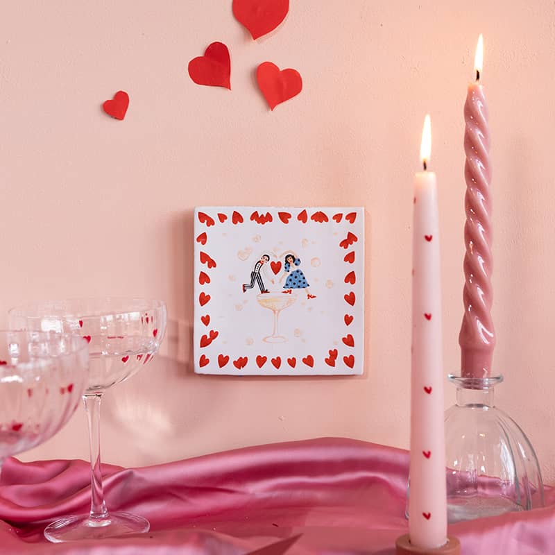 Gepersonaliseerd tegeltje met hartjes omringd door romantische decoratie