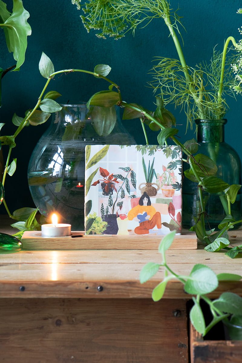 Tegeltje kamerplantvrouw, tussen groene vazen en bladeren gepresenteerd
