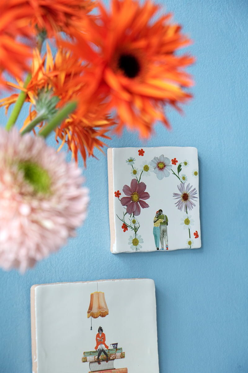 Tegeltjes met bloemen en omhelzend paar tegen blauwe muur