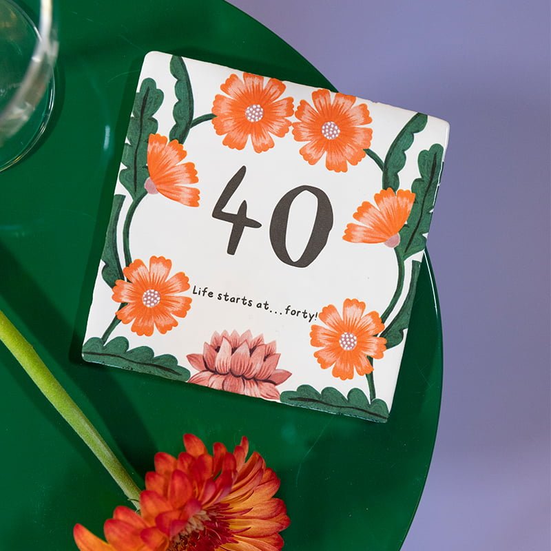 Jubileumcadeau tegeltje met oranje bloemen op groene tafel