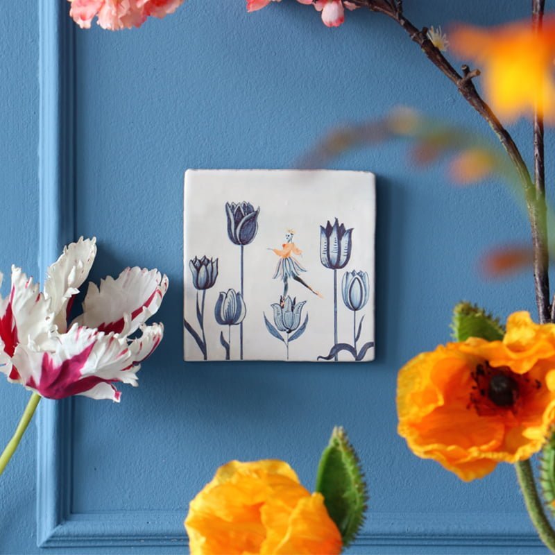 Tegeltje met tulpen en figuur, op blauwe achtergrond geplaatst