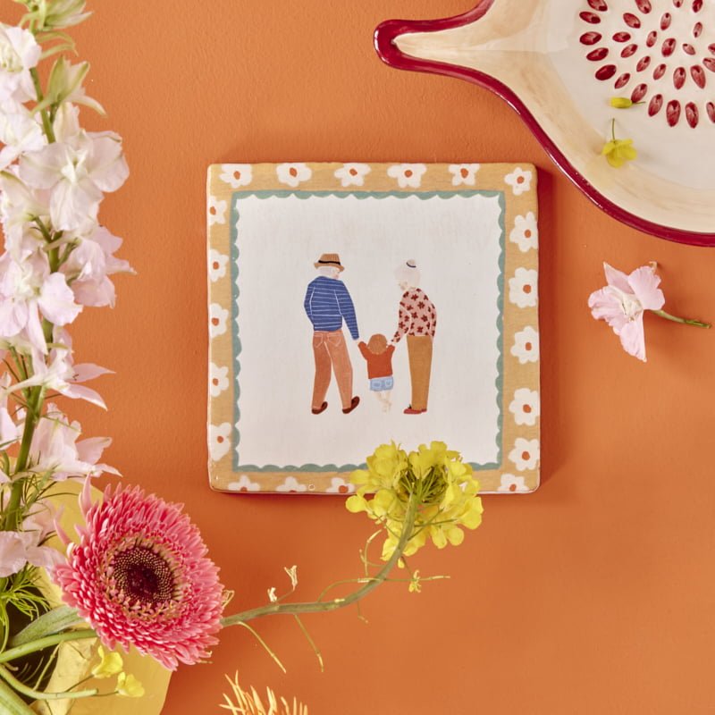 Tegeltje gezinswandeling tegen oranje muur met bloemen en schaal