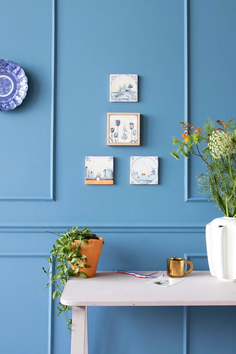 Gepersonaliseerde tegeltjes met blauwe motieven tegen een blauwe muur