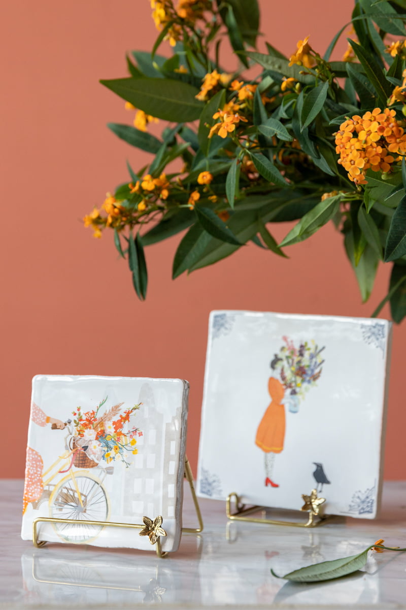 Gouden tegelhouder met bloemmotief tegen een oranje achtergrond
