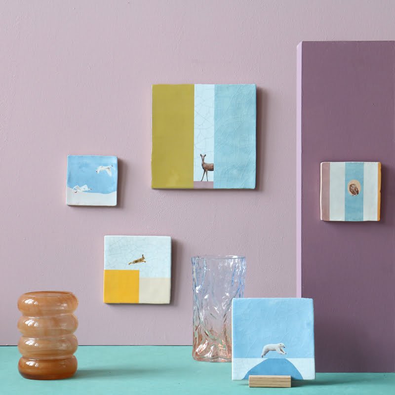 Tegeltjes met dierenmotieven aan gekleurde muur en plank