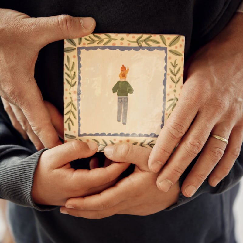 Tegeltje vader met kind vastgehouden door vier handen samen