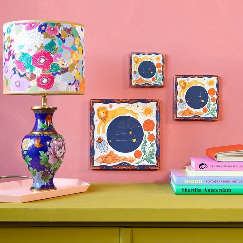 Geboortetegeltje leeuw sterrenbeeld aan roze muur naast lamp