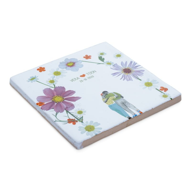 Tegeltje met bloemen en omarmend paar in het midden