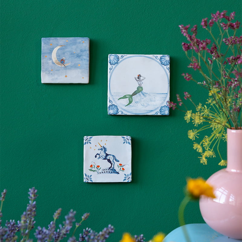 Delfts blauw tegeltje met zeemeermin tegen groene muur gepresenteerd