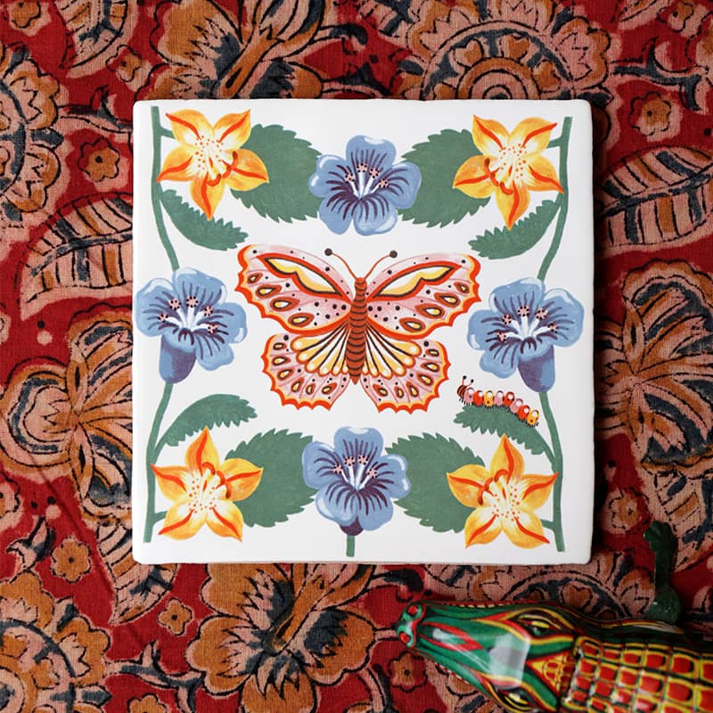 Tegeltje vlinder met bloemen op kleurrijk stoffen achtergrond