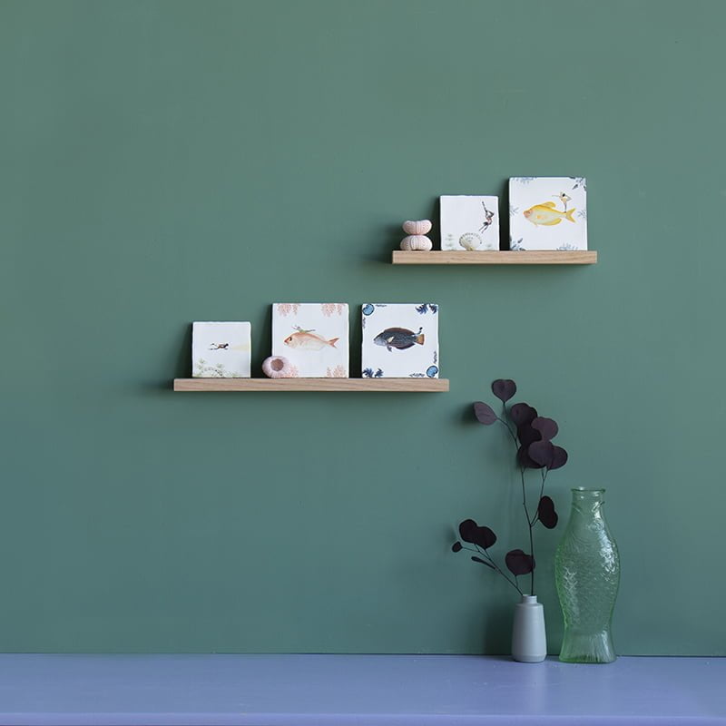Wandplankjes met tegeltjes en decoraties tegen groene muur