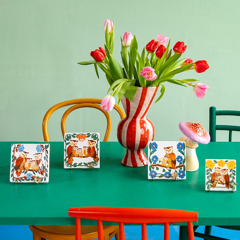 Geboortetegeltjes met uilenmotief op groene tafel met bloemen