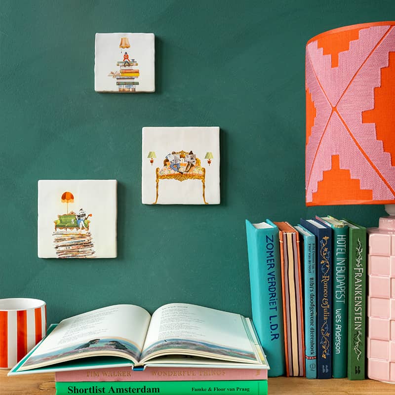 Huwelijkscadeau tegeltjes met boeken thema, weergegeven op groene muur