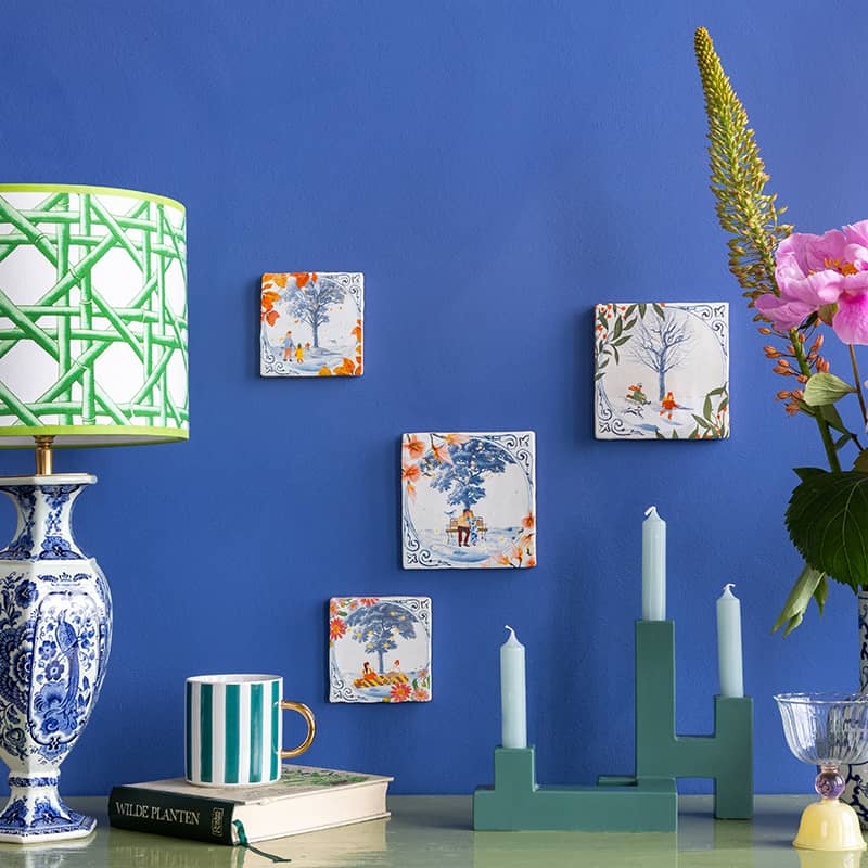 Delfts blauwe tegeltjes met landschapsscènes op blauwe muur gepresenteerd