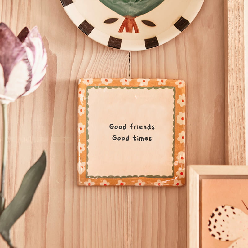 Gepersonaliseerd tegeltje met tekst, hangt aan houten muur