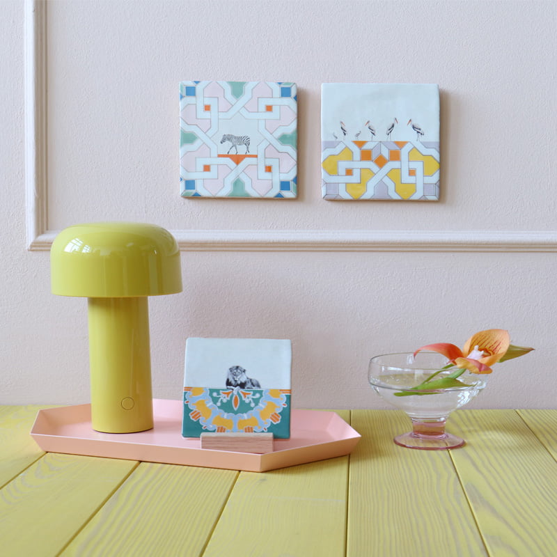 Tegeltje dierenmotieven pastelkleurige wanddecoratie naast gele lamp