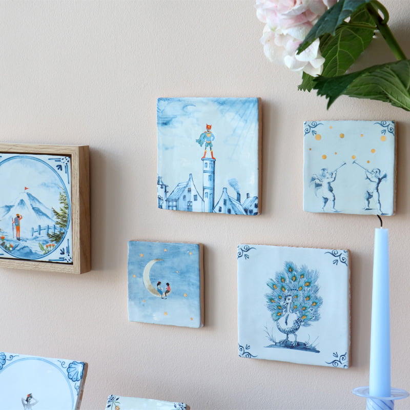 Geboortetegels met diverse illustraties in blauwe tinten aan muur
