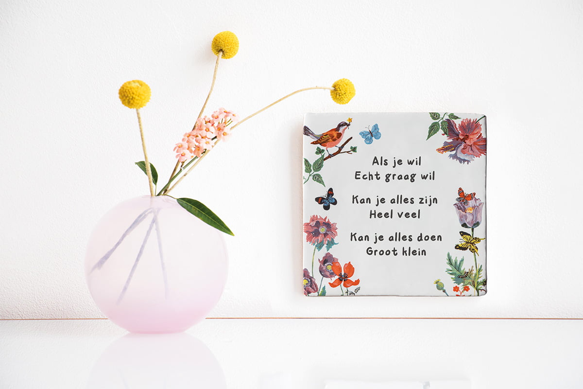 Tegeltje met tekst, bloemen en vogels aan witte muur