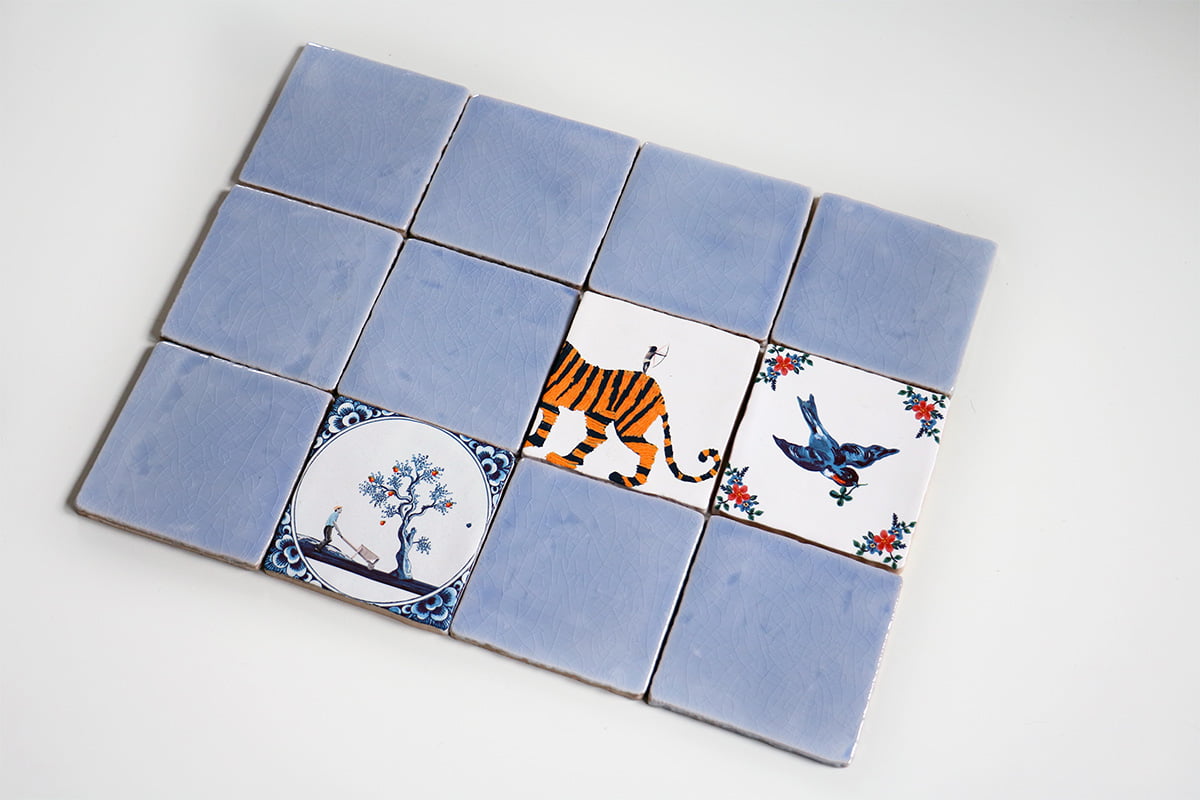 Blauwe tegeltje met dieren en boomtekeningen in wandopstelling