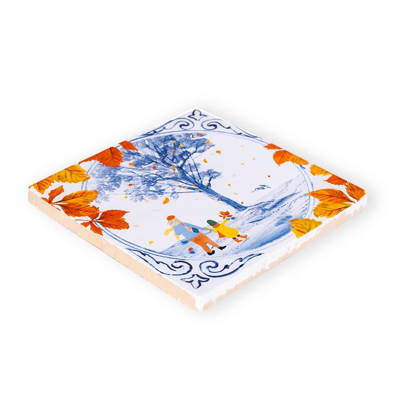 Delfts blauw tegeltje met herfstboom, bladeren en wandelend stelletje