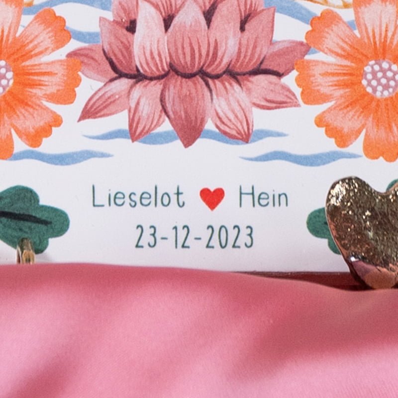 Gepersonaliseerd tegeltje met namen en bloemen, tegen roze achtergrond