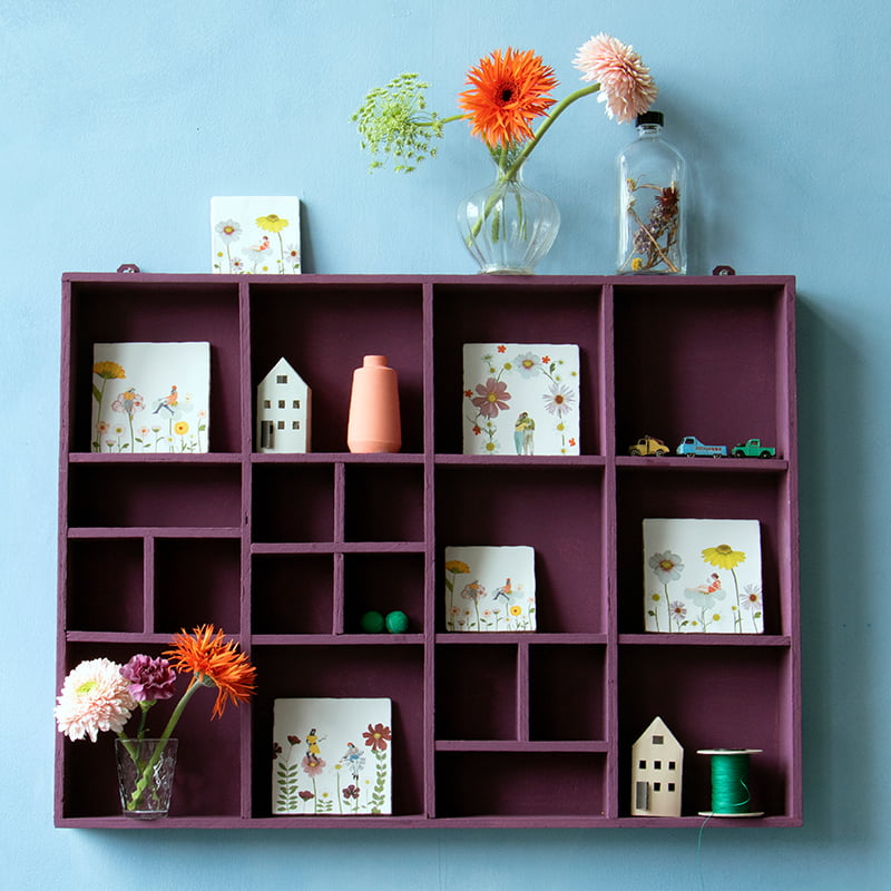 Tegeltjes met bloemen en figuren in paarse vakkenkast