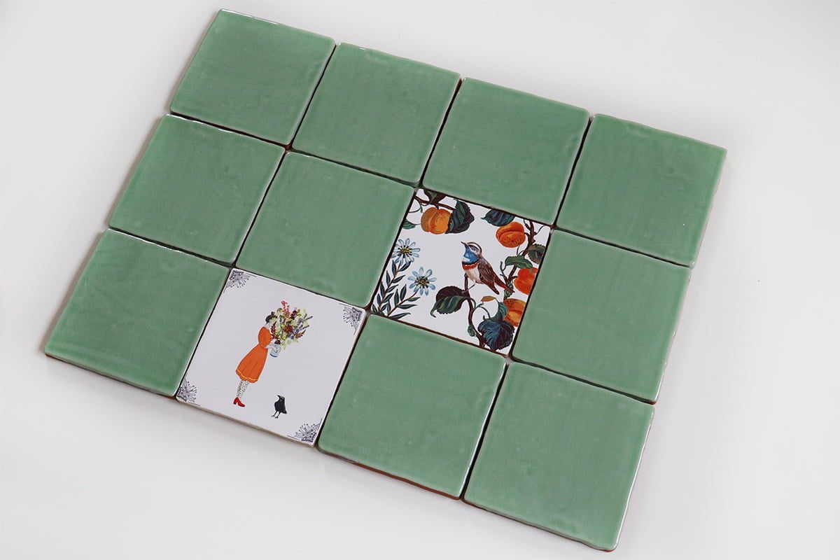 Groene tegels met illustraties van vrouw en vogelmotieven in midden