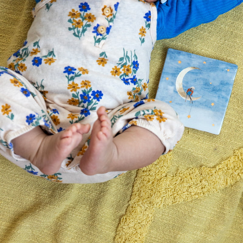 Geboortetegel manetje op maan naast baby op kleed