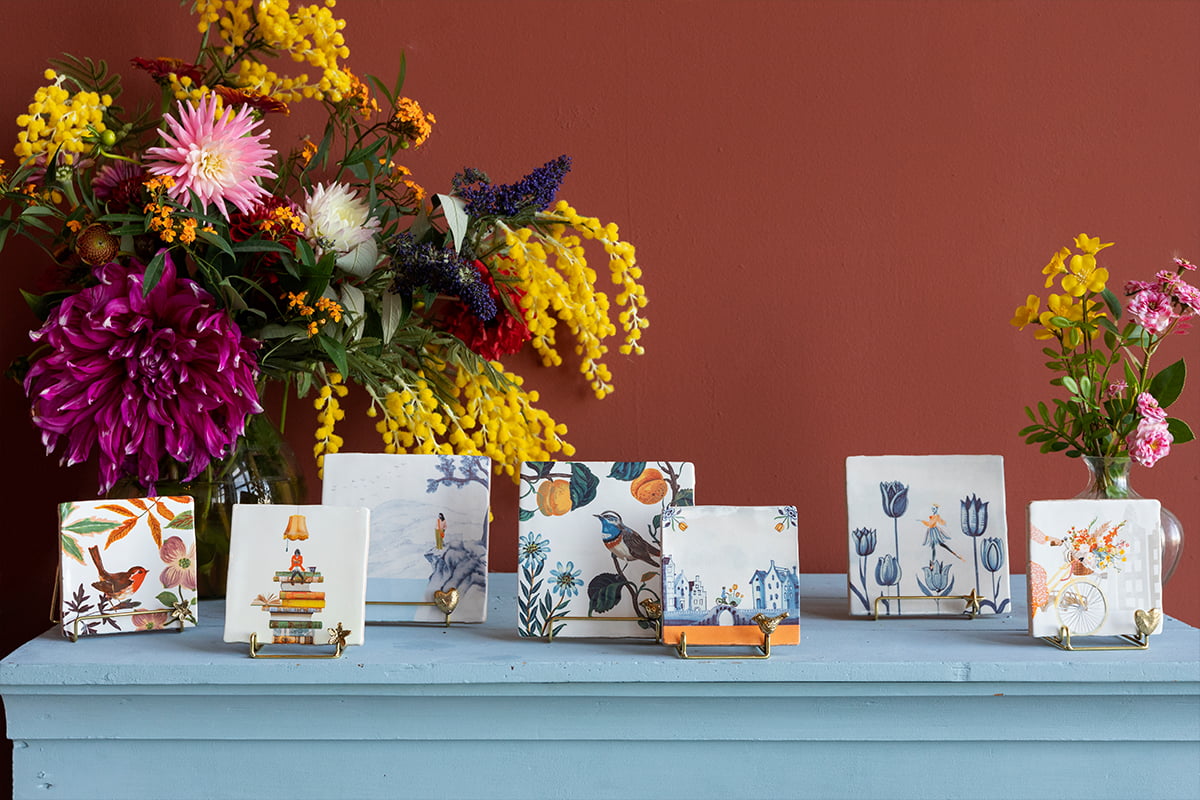 Gouden tegelhouder met decoratieve tegels op een blauwe plank