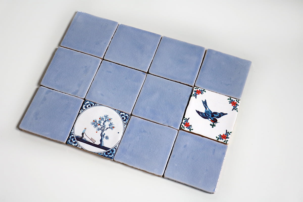 Blauw-witte tegeltjes met boom en vogel, gerangschikt in patroon