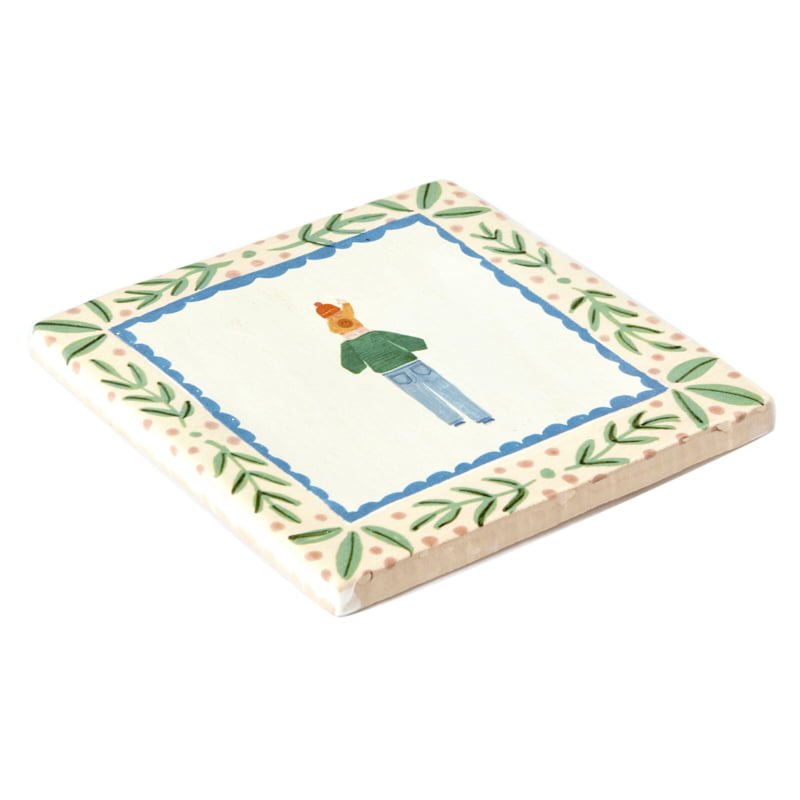 Tegeltje mensfiguur, groene rand decoratief geplaatst op tafel