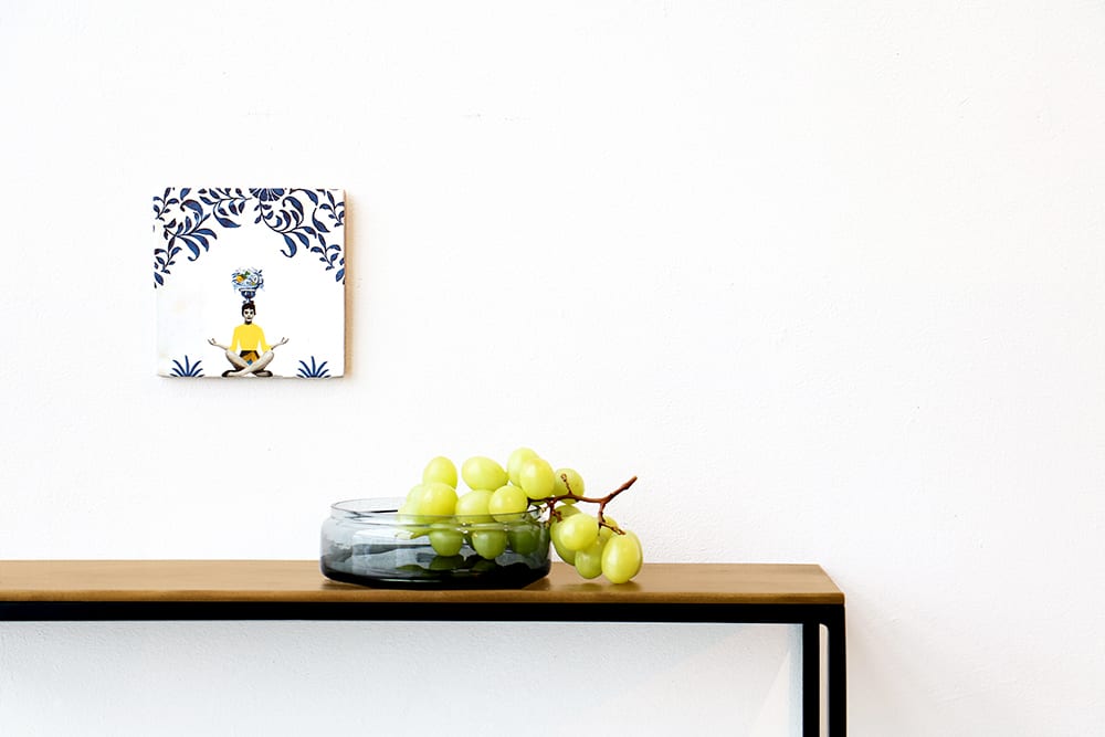 Tegeltje met zittend persoon boven tafel met groene druiven
