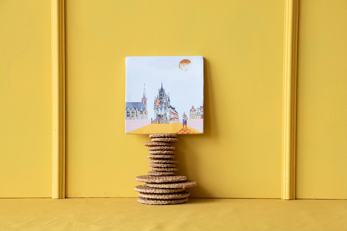 Tegeltje Gouda opgestapeld op stroopwafels tegen okergeel achtergrond