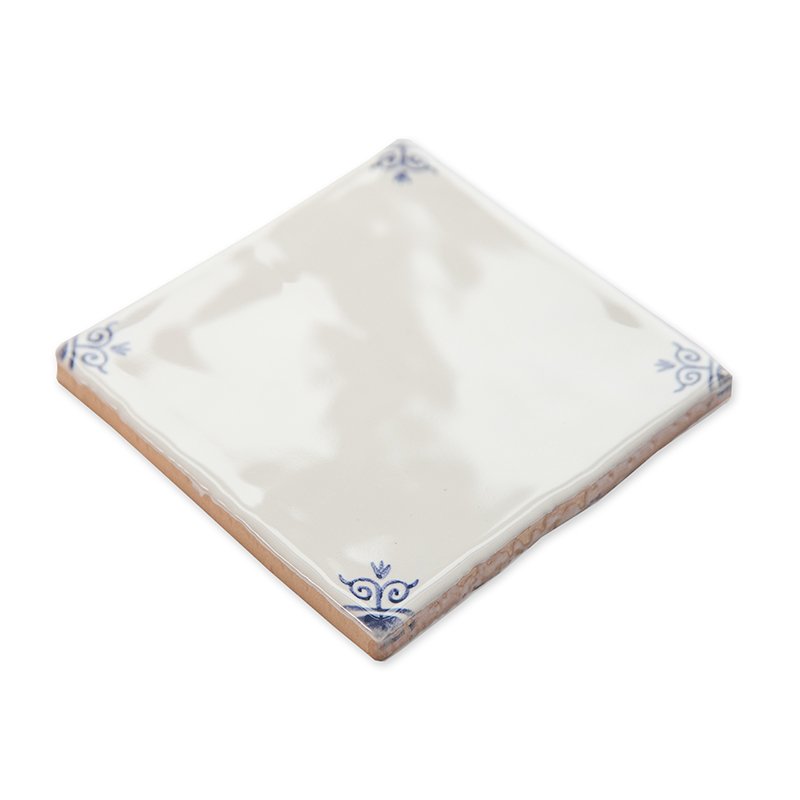 Wit tegeltje met blauwe hoekdecoraties op een witte achtergrond