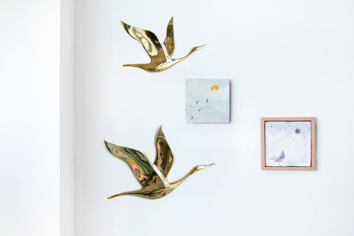 Gepersonaliseerd tegeltje met vogels en zon, aan witte muur