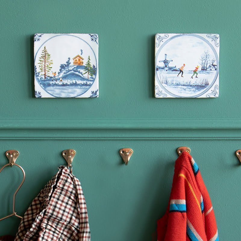 Delfts blauw tegeltje met winterlandschap aan groene muur bevestigd