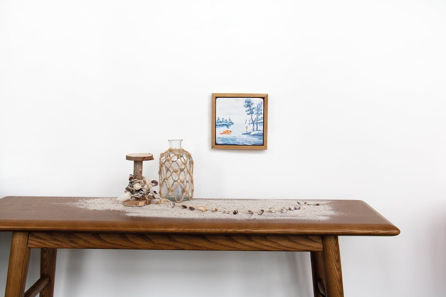 Delfts blauw tegeltje met landschap; hangt boven houten tafel