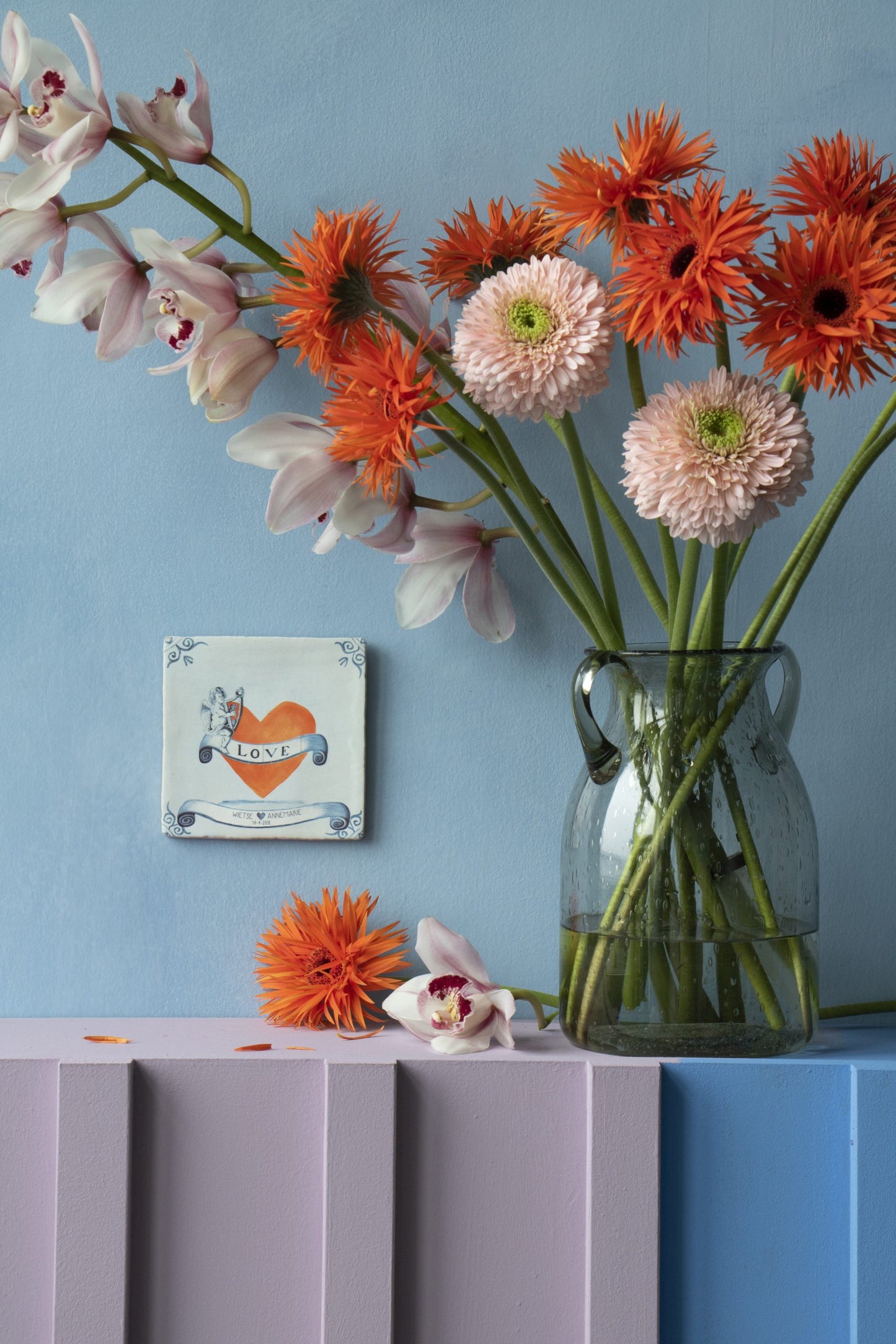 Gepersonaliseerd tegeltje met "Love" naast vaas met kleurrijke bloemen